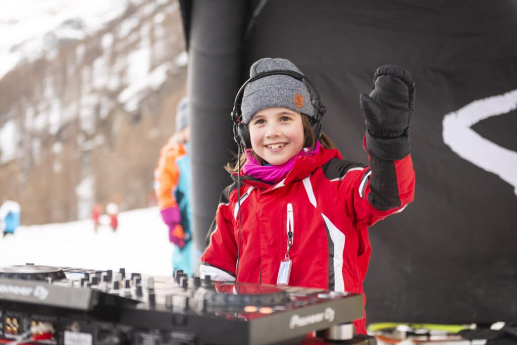 Kind zwaait naar de camera en zit achter de dj boot